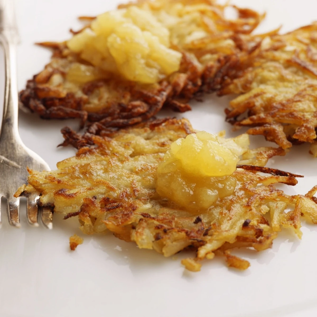 Goldene, knusprige Kartoffelpuffer mit süßer, hausgemachter Apfelsoße serviert.